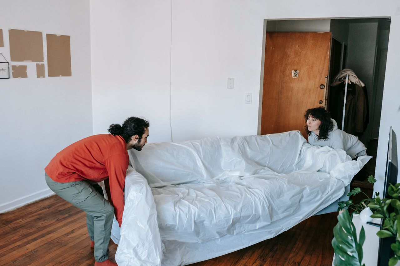 about-01 A couple collaboratively lifting a couch while moving into a new apartment.
